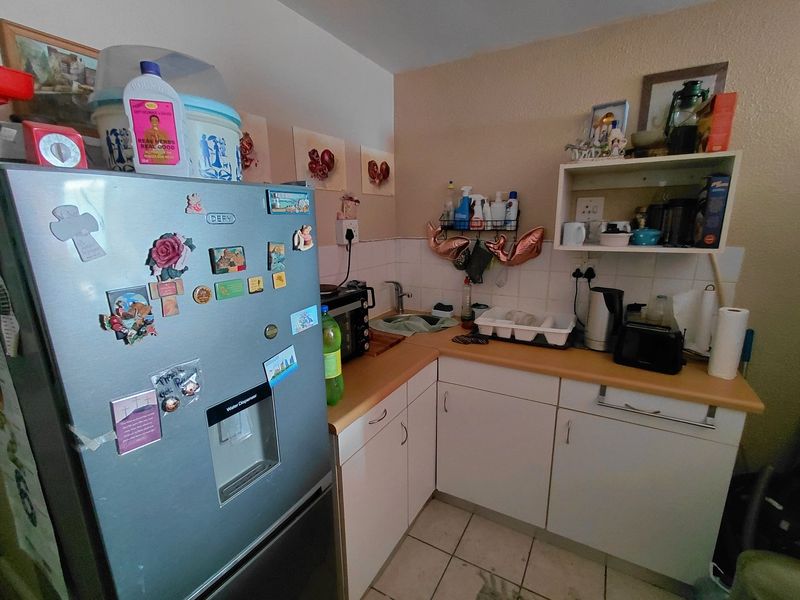 Compact kitchen area featuring laminate countertops, tiled backsplash, and white cabinetry, providing functional storage and preparation space.