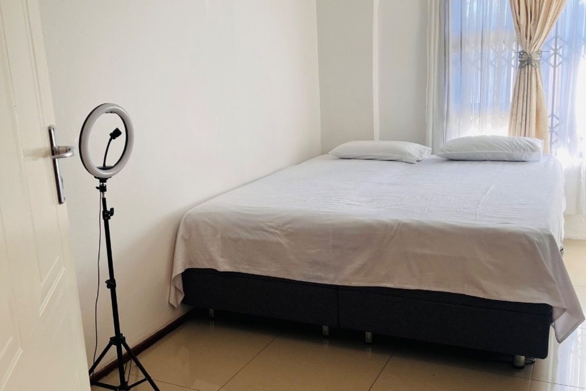 A bedroom featuring tiled flooring and decorative ceiling cornicing, with a window fitted with a security gate.