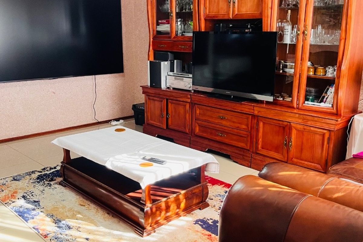 A living room featuring tiled flooring, crown molding, and a ceiling fan, providing a functional space for relaxation and entertainment.
