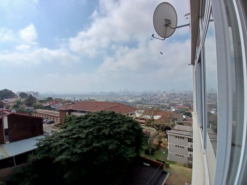 Elevated urban view overlooking the surrounding neighbourhood and city skyline, captured from an apartment window.