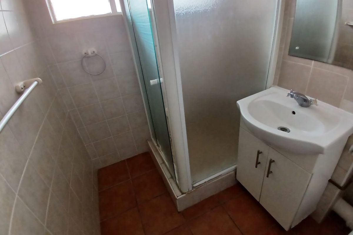 A functional bathroom featuring a shower enclosure, vanity cabinet with basin, and tiled finishes throughout.