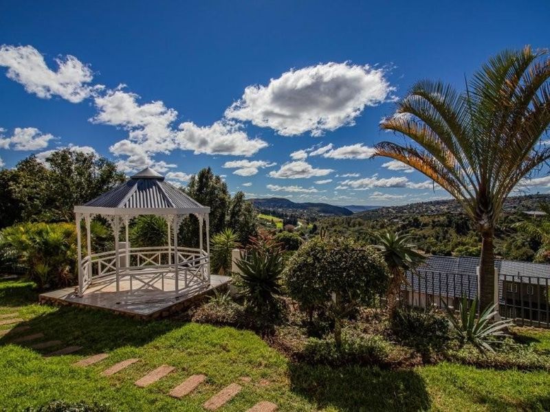 A well-maintained garden featuring a white gazebo, stone pathway, and expansive views of the surrounding landscape.