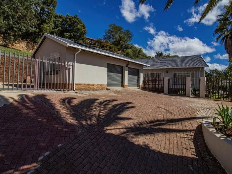 Front exterior view of the property featuring a paved driveway, double garage, and secure perimeter fencing.
