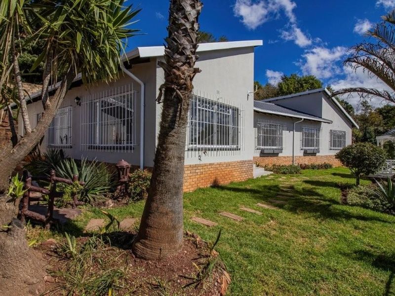 Rear view of the house featuring a brick base, security bars on windows, and a landscaped garden with a stone pathway.