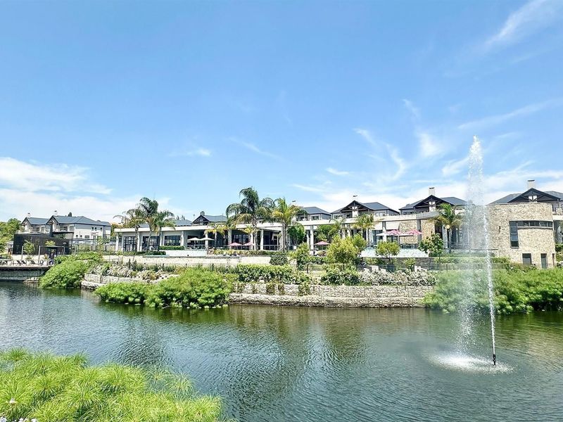 A scenic view of the apartment complex exterior featuring a landscaped garden, stone retaining walls, and a central water fountain feature.