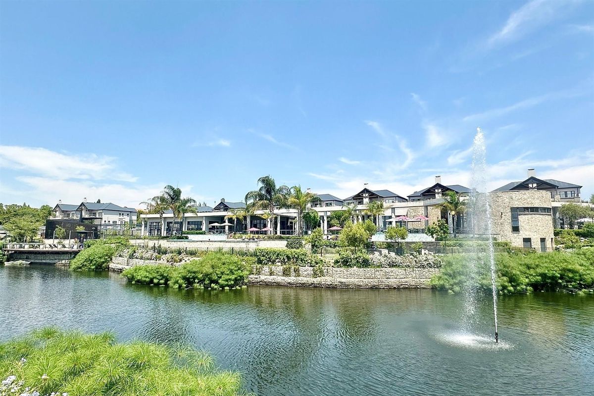 A scenic view of the apartment complex exterior featuring a landscaped garden, stone retaining walls, and a central water fountain feature.