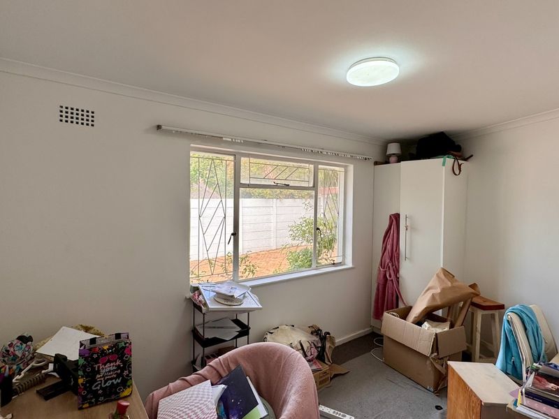 A bedroom featuring a built-in wardrobe, security bars on the window, and a ceiling light fixture.