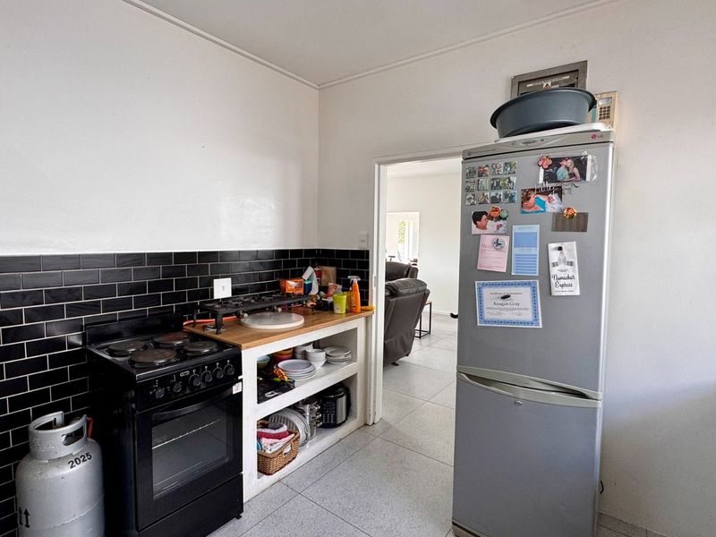 A functional kitchen area featuring black subway tile splashbacks, tiled flooring, and built-in open shelving units.
