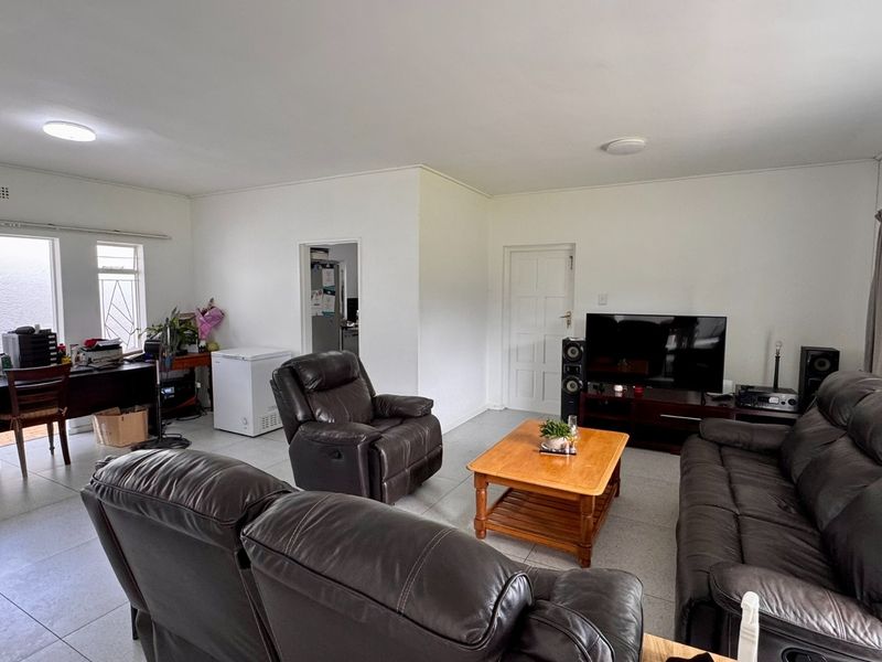 A spacious living room featuring neutral tiled flooring and ample natural light, providing a versatile layout for comfortable family living.