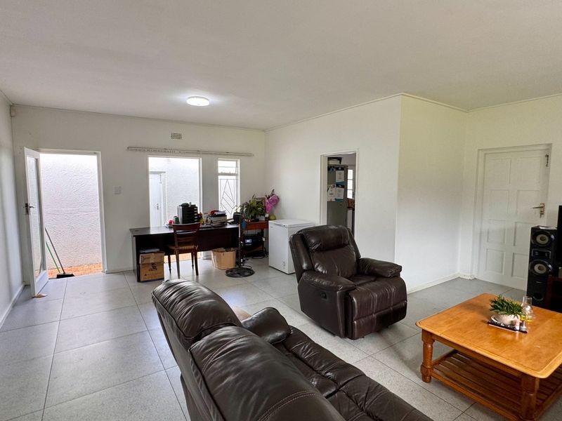 Spacious living area featuring neutral tiled flooring and direct access to an outdoor space, offering a versatile layout for comfortable family living.