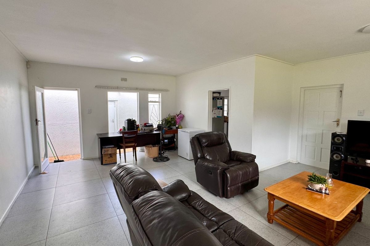 Spacious living area featuring neutral tiled flooring and direct access to an outdoor space, offering a versatile layout for comfortable family living.