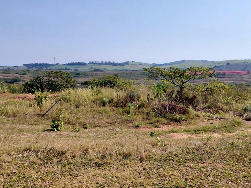 A wide-angle view of the vacant residential land, showcasing the natural landscape and surrounding hilly terrain.