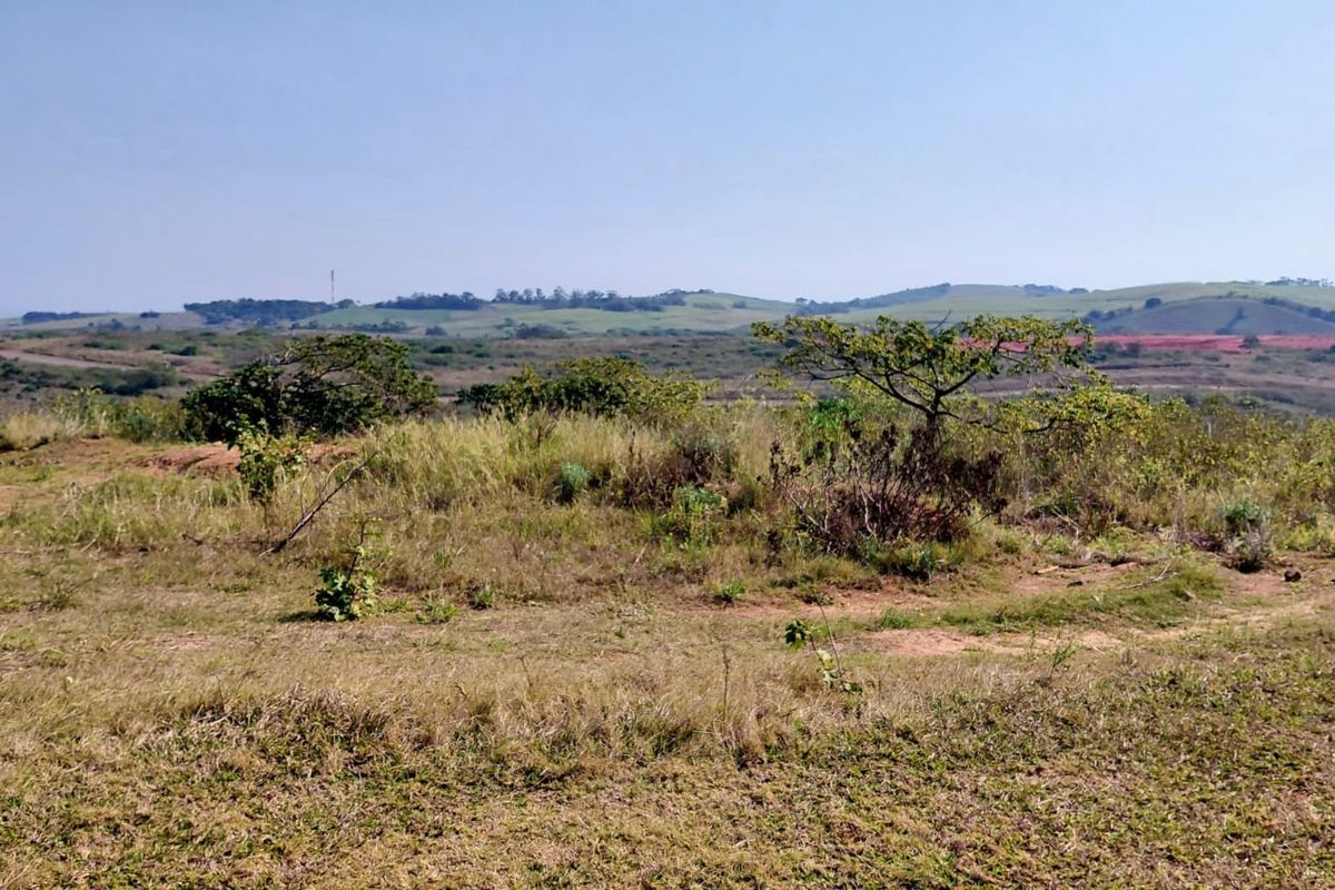 A wide-angle view of the vacant residential land, showcasing the natural landscape and surrounding hilly terrain.