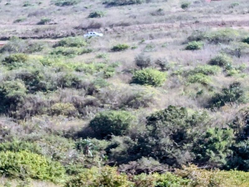 An aerial view of a vacant residential plot featuring natural vegetation and undeveloped terrain.