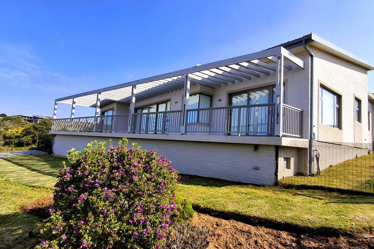 Rear view of the property featuring a spacious elevated balcony with a pergola, sliding glass doors, and well-maintained brick exterior finishes.