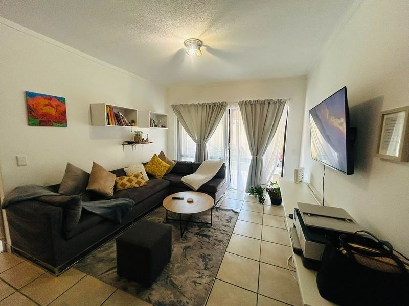 A comfortable living room featuring ceramic floor tiles, built-in wall shelving, and a sliding glass door providing access to the outdoor area.