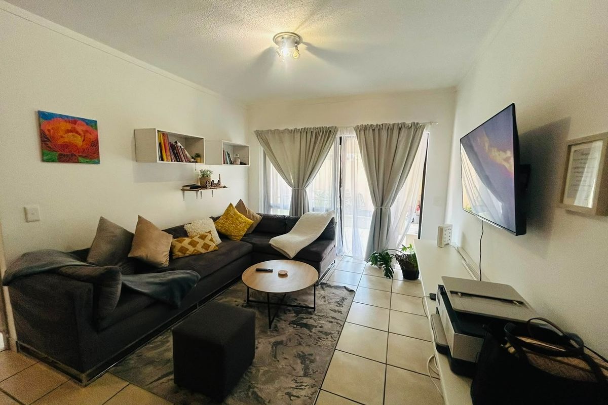 A comfortable living room featuring ceramic floor tiles, built-in wall shelving, and a sliding glass door providing access to the outdoor area.