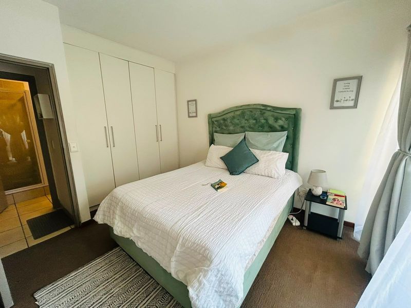 A well-maintained bedroom featuring built-in cupboards and direct access to an en-suite bathroom, offering a functional and comfortable living space.