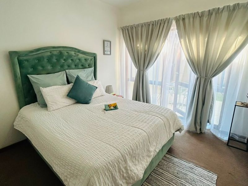 A well-lit bedroom featuring carpeted flooring and a large sliding glass door that provides access to an outdoor area.
