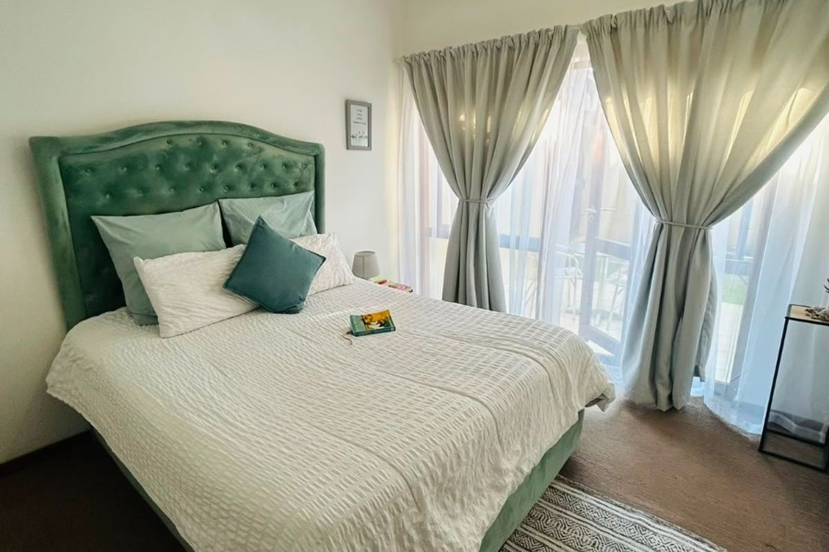 A well-lit bedroom featuring carpeted flooring and a large sliding glass door that provides access to an outdoor area.