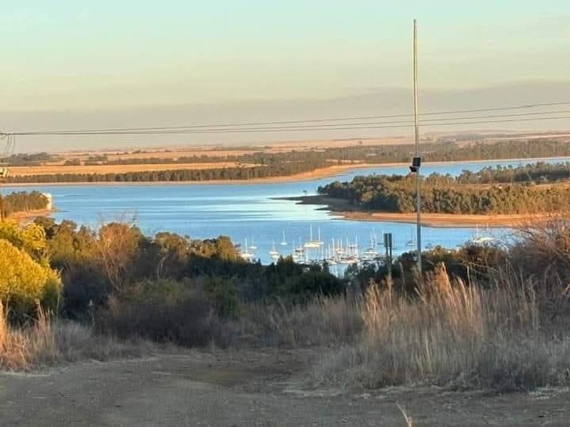Scenic elevated view overlooking a large dam or lake with a marina and surrounding natural landscape.