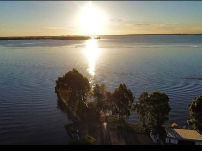 A scenic aerial view of the waterfront property at sunset, highlighting the natural landscape and tranquil water setting.