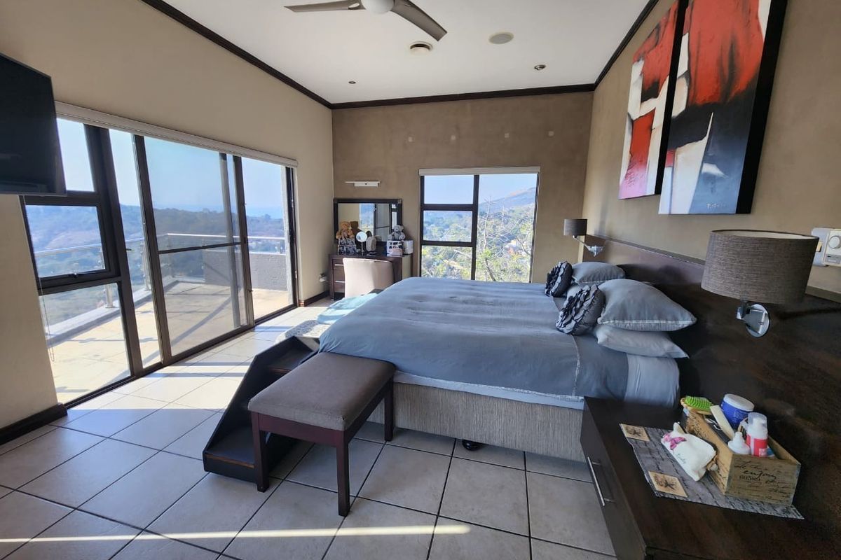 Spacious bedroom featuring large sliding glass doors with scenic views, tiled flooring, recessed lighting, and a built-in headboard.