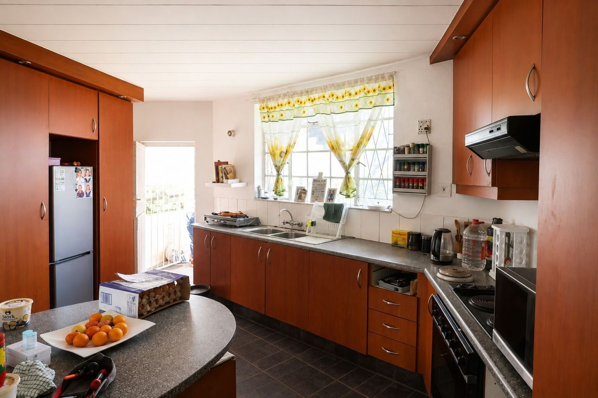 A functional kitchen featuring wood-look laminate cabinetry, laminate countertops, a built-in oven with hob, and direct access to an outdoor area.