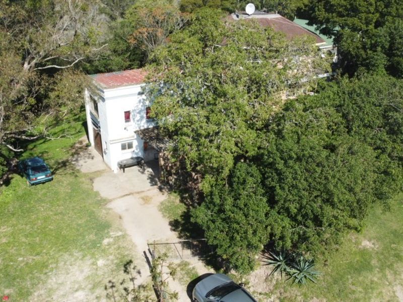 Aerial view of the property showing the main building structure, surrounding mature trees, and concrete driveway access.