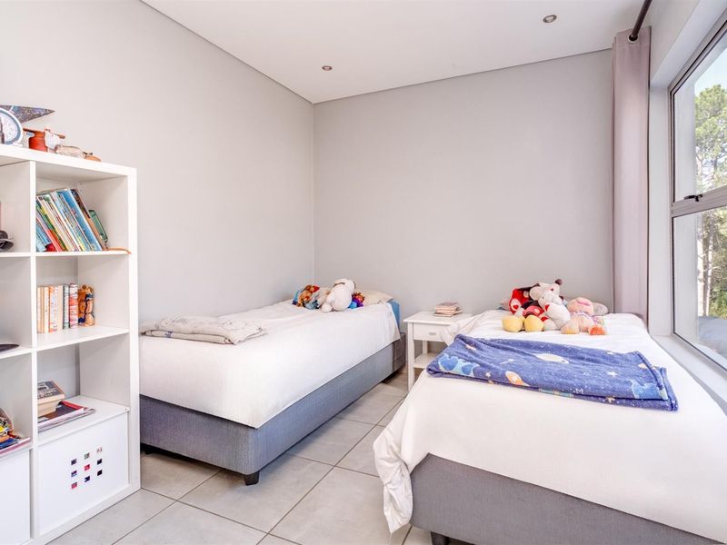 A bright and well-maintained bedroom featuring tiled flooring, recessed downlighting, and large aluminium-framed windows allowing for natural light.