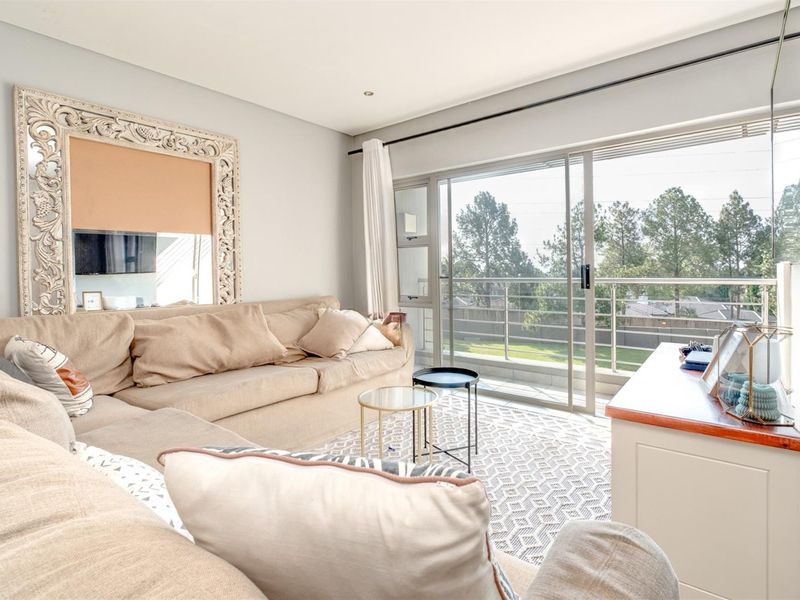 Bright living room featuring large sliding glass doors that open onto a balcony, providing natural light and outdoor access.