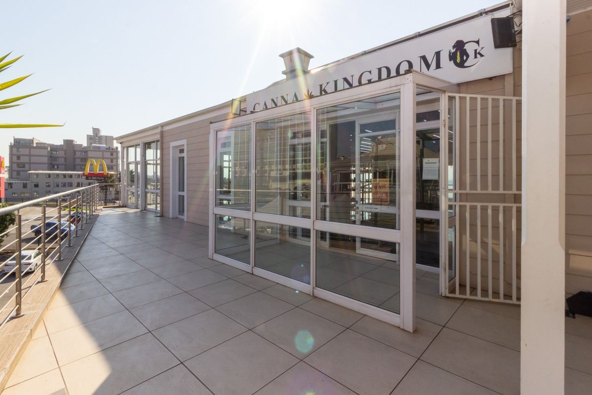 A spacious, tiled outdoor balcony area featuring glass sliding doors, metal security gates, and a metal safety railing.