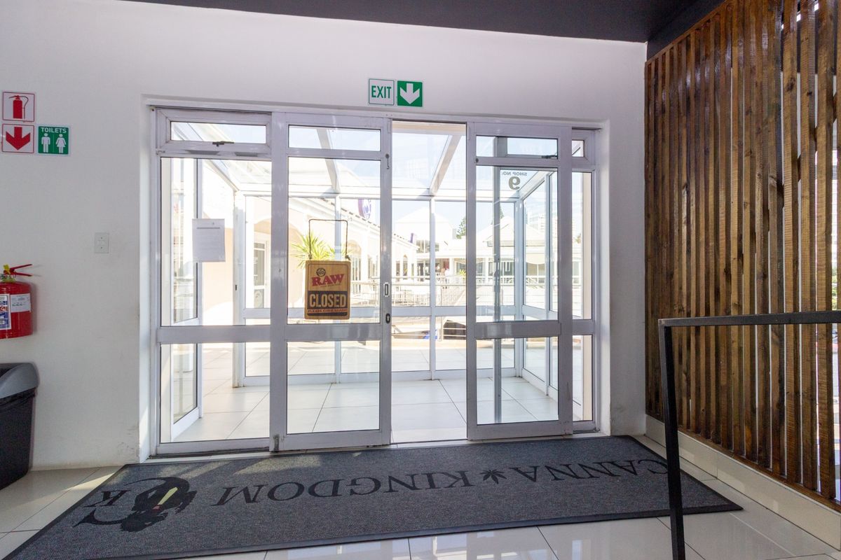 A clean, modern restaurant entrance featuring white tiled floors, aluminium glass sliding doors, and decorative timber slat wall paneling.