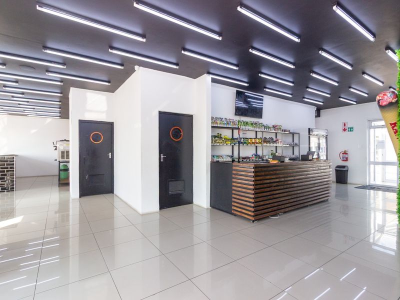 Modern open-plan restaurant interior featuring a large service counter, tiled flooring, and contemporary strip lighting throughout the space.