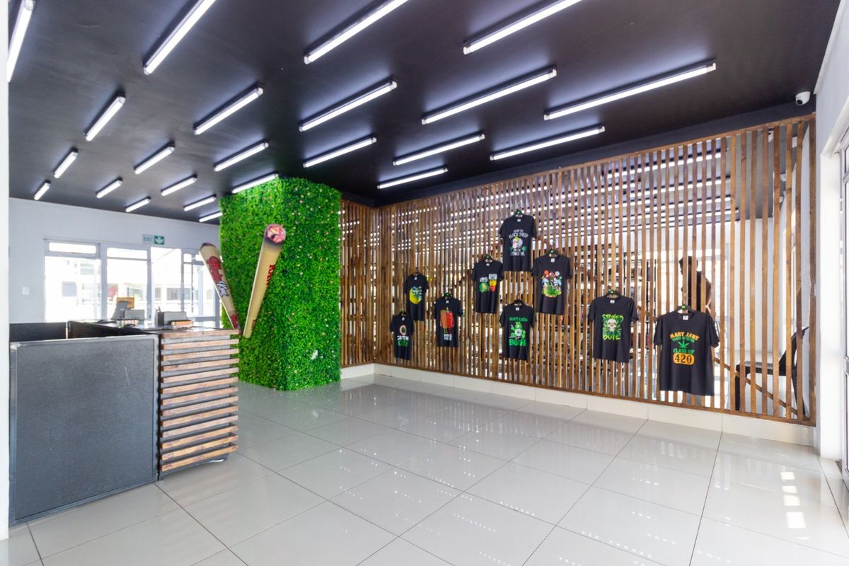 Modern commercial interior featuring a slatted timber wall, artificial green feature wall, high-gloss tiled flooring, and linear ceiling lighting.