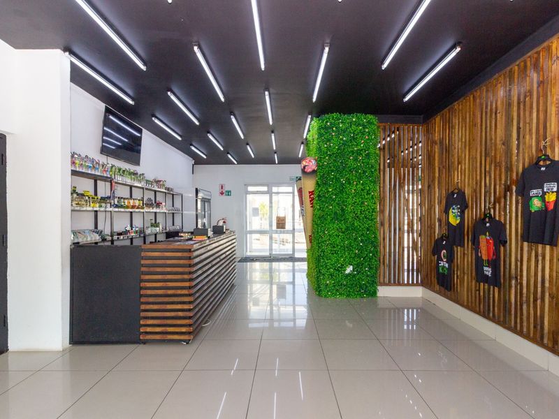 Modern restaurant interior featuring a built-in service counter, linear LED lighting, vertical timber slat wall cladding, and a decorative artificial green wall feature.