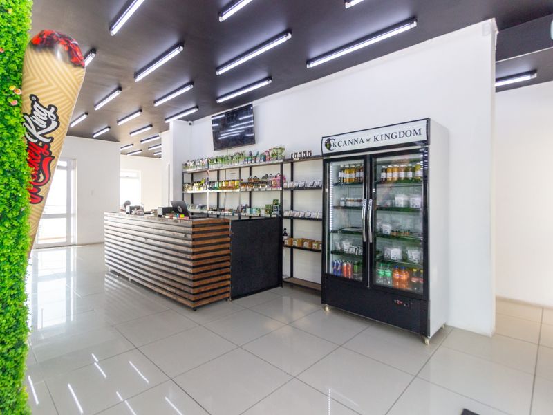 A modern commercial retail space featuring a built-in service counter, tiled flooring, and integrated commercial refrigeration units under linear ceiling lighting.