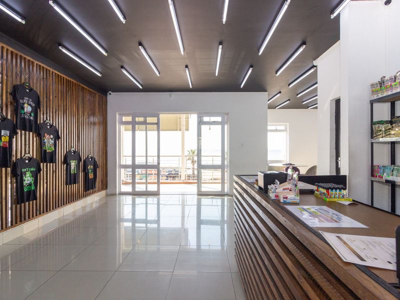 A bright, modern entrance area featuring a built-in service counter, slatted timber wall accents, and polished tiled flooring with ample natural light.
