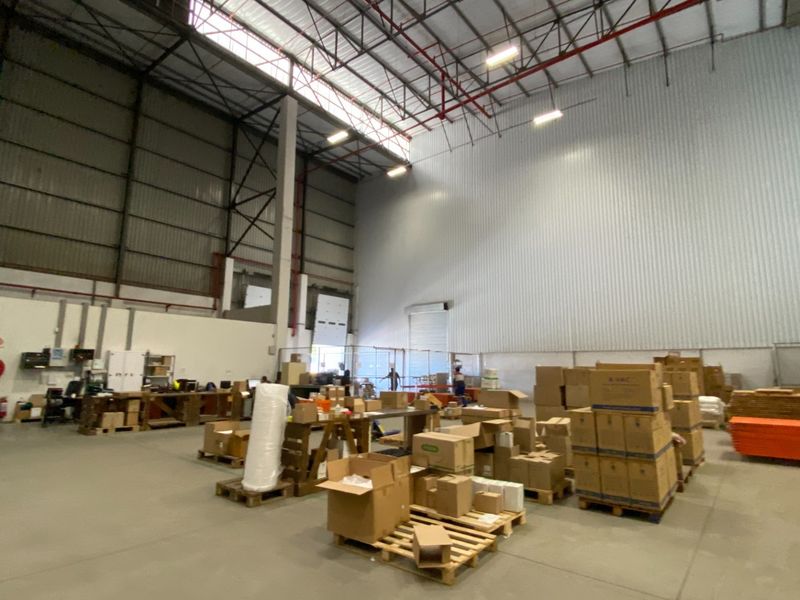 Spacious industrial warehouse featuring high-clearance ceilings, exposed steel trusses, fire sprinkler system, and durable concrete flooring, suitable for storage or manufacturing operations.