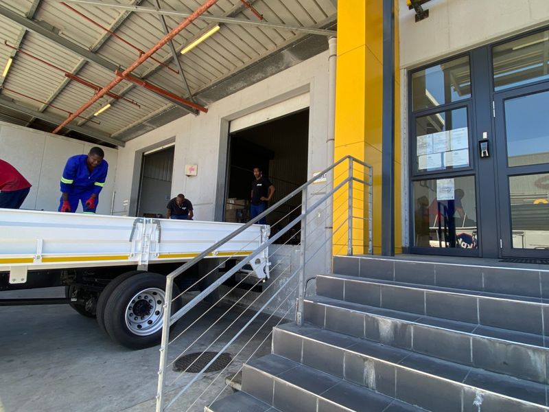 Industrial facility exterior featuring a loading bay with roller shutter access, concrete hardstand, and a modern tiled entrance with glass door.