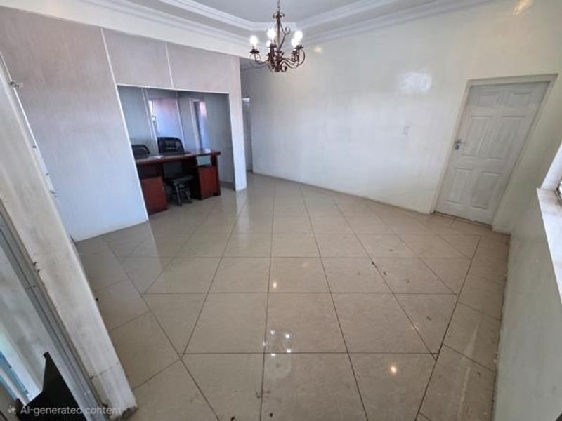A spacious office area featuring tiled flooring, a built-in desk nook, and a classic chandelier, offering a clean and functional workspace.