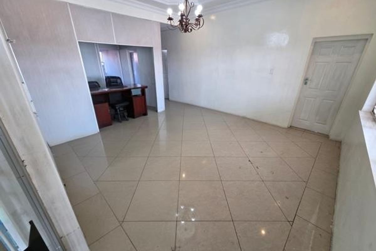 A spacious office area featuring tiled flooring, a built-in desk nook, and a classic chandelier, offering a clean and functional workspace.