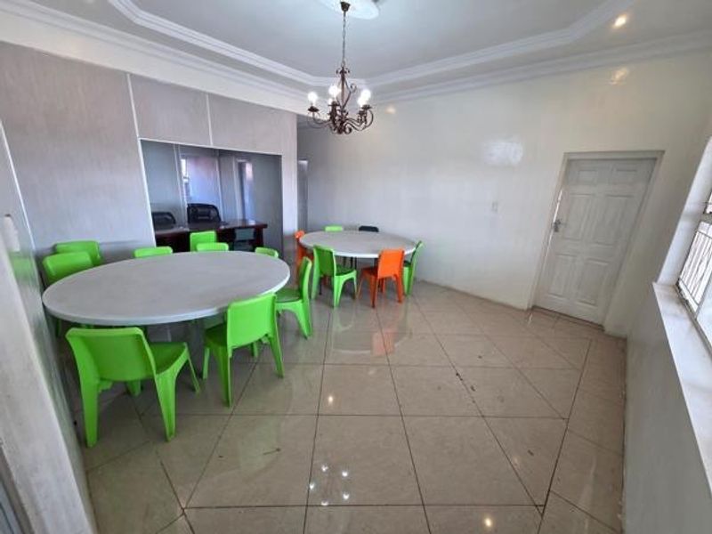 Spacious office area featuring tiled flooring, decorative cove ceiling, and a central chandelier, providing a functional workspace with a neutral interior finish.