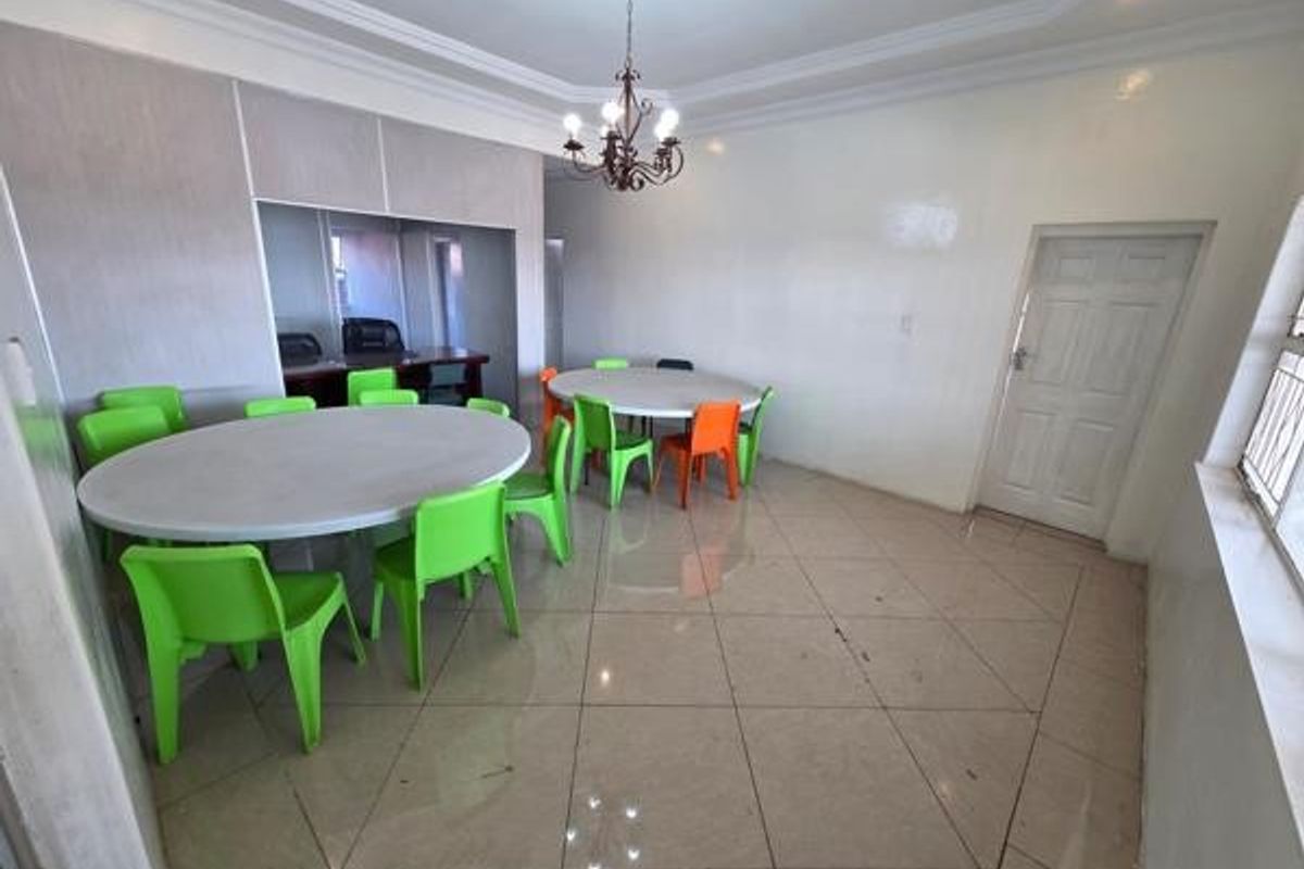 Spacious office area featuring tiled flooring, decorative cove ceiling, and a central chandelier, providing a functional workspace with a neutral interior finish.