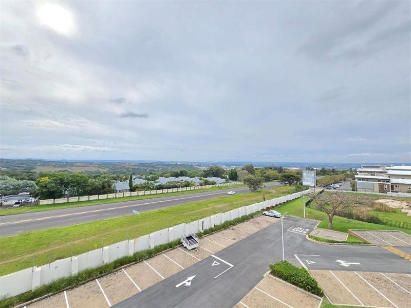 Elevated view overlooking the apartment complex parking area, perimeter security fencing, and surrounding landscape.
