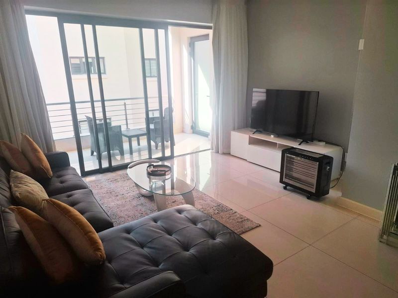 A bright living room featuring large sliding glass doors that provide seamless access to an outdoor balcony area.