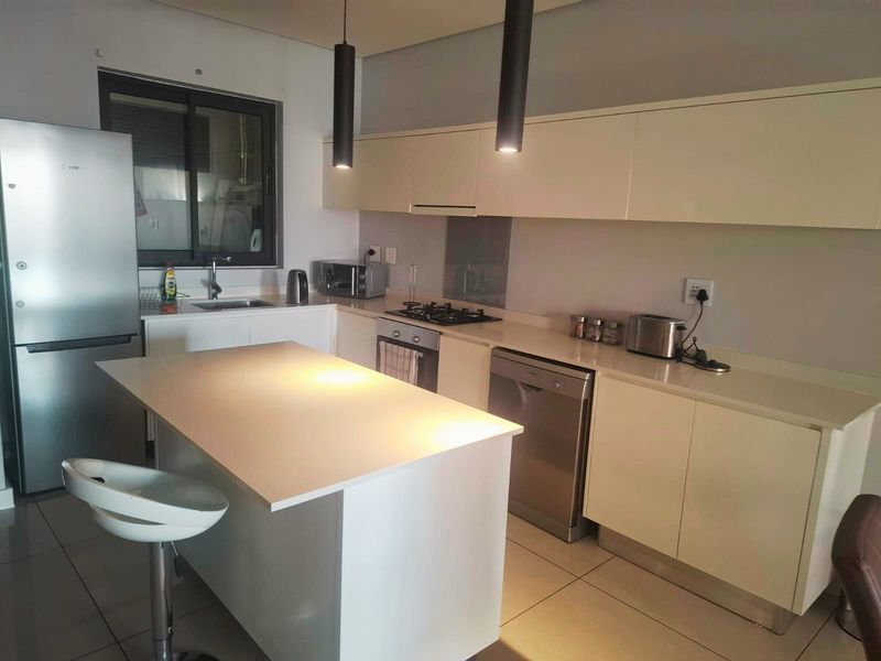 Modern kitchen featuring sleek built-in cabinetry, stone countertops, a central island, and integrated gas hob, offering a functional and contemporary cooking space.