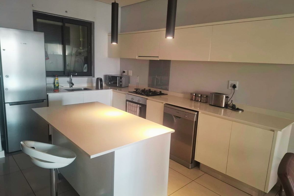 Modern kitchen featuring sleek built-in cabinetry, stone countertops, a central island, and integrated gas hob, offering a functional and contemporary cooking space.
