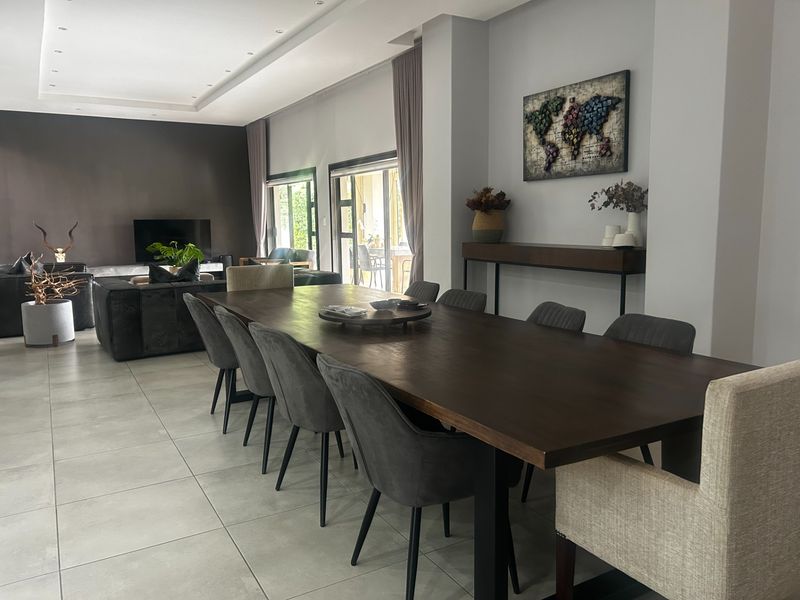 Spacious open-plan living and dining area featuring large format floor tiles, recessed ceiling lighting, and sliding glass doors leading to the outdoor space.