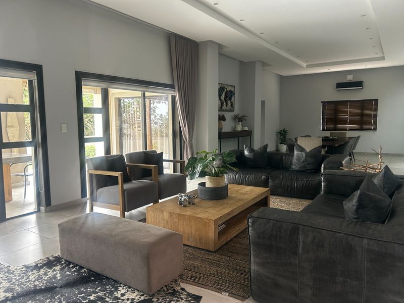 Spacious open-plan living area featuring tiled floors, recessed ceiling lighting, and large sliding glass doors providing seamless access to the outdoor patio.